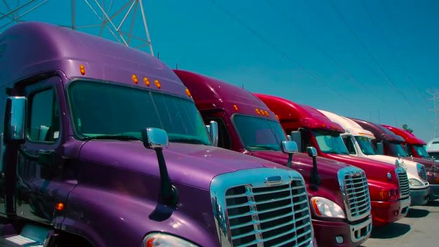 Slow pan up of purple freight liner truck parked in an outdoor lot