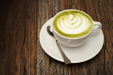 Hot green tea matcha latte on wooden table in the cafe
