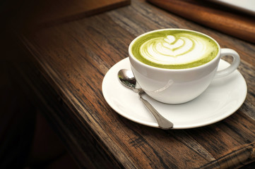 Hot green tea matcha latte on wooden table in the cafe
