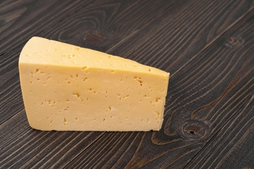 The triangular piece of cheese on a dark wooden surface