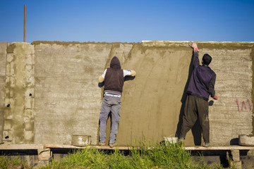Iraqi Arab worker in project working in plastering of new constructed wall in Iraqi desert at...