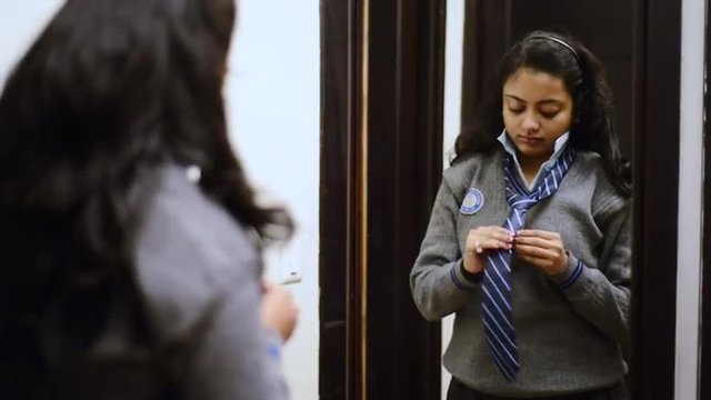 Locked-on shot of a schoolgirl getting dressed