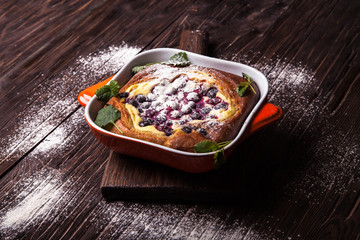 cake with berries in a baking dish, sprinkle with powdered sugar
