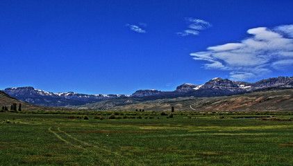 Dubois Wyoming pasture / farming field under cumulus / cirrus cloudscape with Absaroka Mountain range in the background