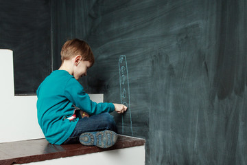  Little boy is drawing on a blackdoard