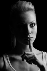 Obraz premium Mystery woman in shadow with finger on lips gesturing silence. D