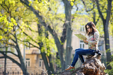 Fototapeta na wymiar young girl sitting in the park and reading a map