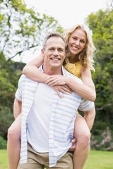 Obraz premium Happy husband giving piggy back to his wife