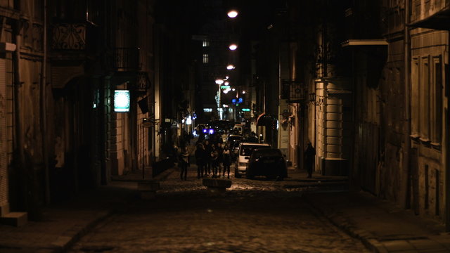 People walking by a street of an old traditional town at night. Establishing shot. 