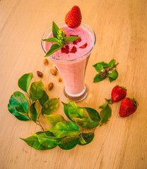 A glass of strawberry smoothie cocktail with mint and herbs on a