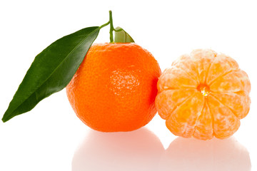 Fresh unpeeled orange mandarin citrus with green leafs and half