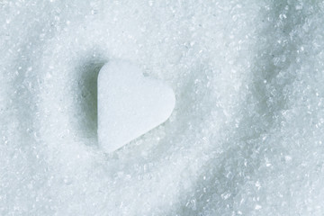 Heart shape on white sugar abstract closeup
