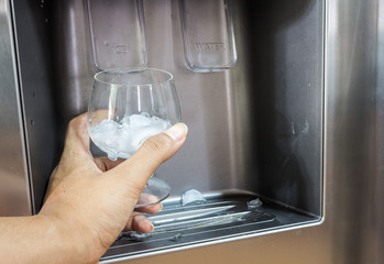 Hand with ice dispenser and glass