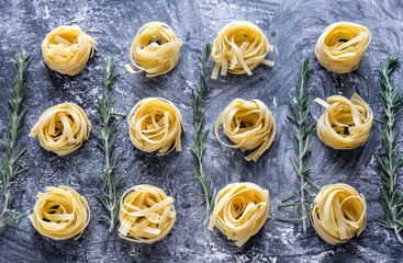 Raw tagliatelle nido on the flour-dusted black wooden background