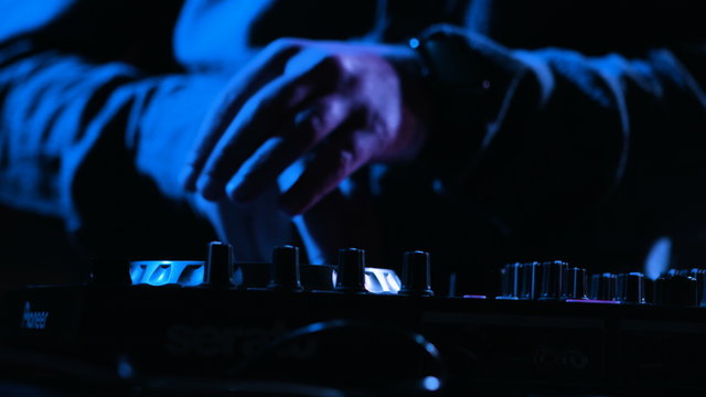 Close-up footage of a male DJs  hands mixing music at a party by using his control desk,artist is using his instrument for playing music at a stage.
