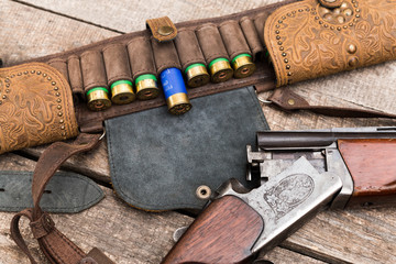 Fototapeta na wymiar Hunting shotgun and ammunition on wooden background