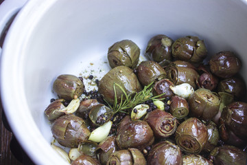 Artischockenherzen mit Knoblauch, Rosmarin und Olivenöl mariniert in einer weien Schüssel