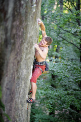 rock climber climbing up a steep rocky wall in summer time