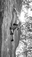 Naklejka premium Young man rock-climbing on large boulder
