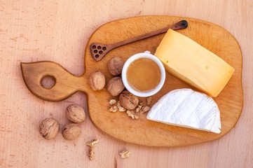 Cheese, walnuts, honey on a wooden table