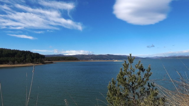 Snow caped mountain on top of big lake blue sky white clouds, Iskar Lake, Bulgaria