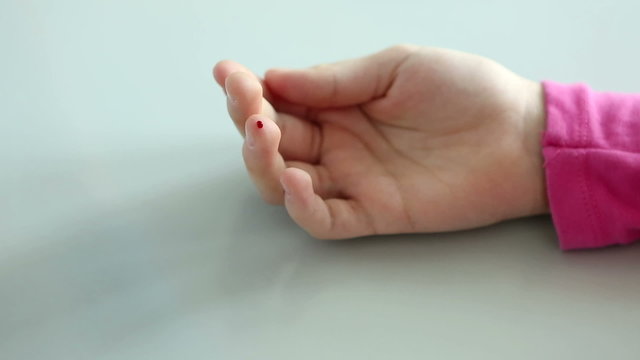 Nurse takes blood from a finger of child in medical laboratory.