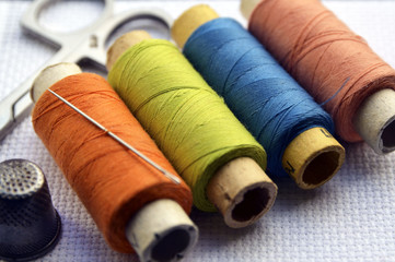 Fototapeta na wymiar Sewing tools on white texture.Sewing kit.Scissors, thimble, bobbins with thread and needle.