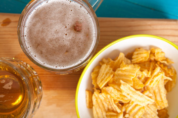 potato chips and a mug of beer on the table; view from above