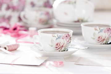 Three cups of tea on a white background. Tea in a bright cups with roses. Vintage style. Bright hues.