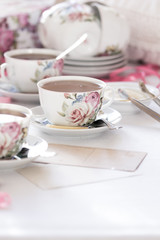 Three cups of tea on a white background. Tea in a bright cups with roses. Vintage style. Bright hues.