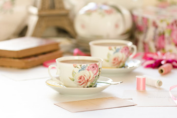 Two cups of tea on a white background. Tea in a bright cups with roses. Vintage style. Bright hues.