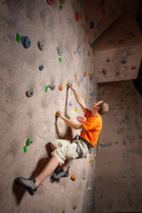 Obraz na płótnie Canvas Young man climbing on practical wall in gym