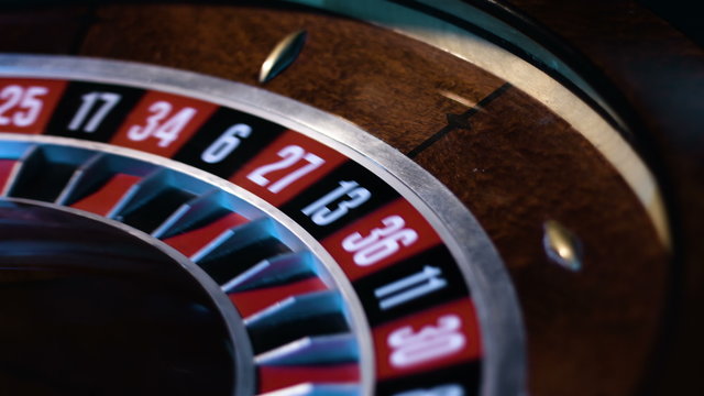 Close-up footage of a small white ball gets into a slot in a russian roulette wheel.  