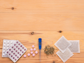 tablets, drops, herbals and thermometer on a wooden background
