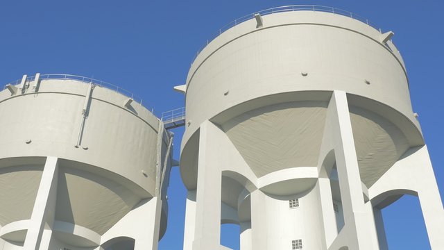 Concrete water towers in front of blue sky slow motion 4K 2160p UHD footage - Water tower made of concrete slow panning 4K 3840X2160 UltraHD video