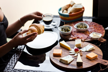 Womans Hand with Croissant cheese and meat plates and Coffee. Fr