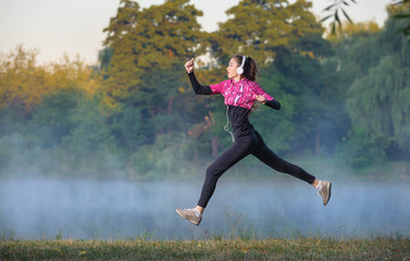 fit girl working out in morning near the lake with her headphone