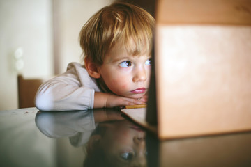 Little serious and lonely child Girl sitting and looking on tablet laptop