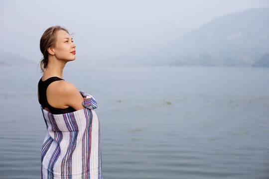 Young beautiful woman in comfortable warm blanket on Mountain Lake. Calm and tranquil, relax outdoor