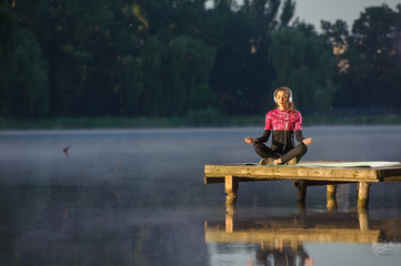 young woman meditating in nature on the river