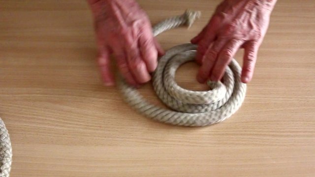 Esecuzione di nodi marinari con corda di canapa su piano in legno