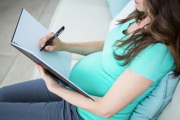 Naklejka premium Pregnant woman writing on document