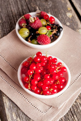 bowl of red currant on wooden background, vertical close-up