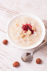Oatmeal with milk, nuts and strawberry jam and milk jug