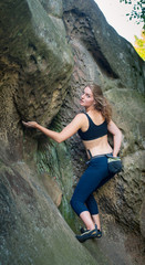 young woman climbing on large boulders