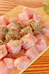 Pile of raw beef chunks on the wooden cutting board, garlic, spices, olive oil