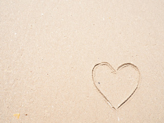 Heart-shape drawing on the sandy beach with sea background