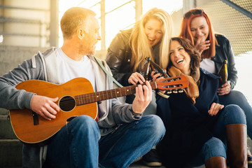 Happy group of friends enjoying  playing guitar and singing toge