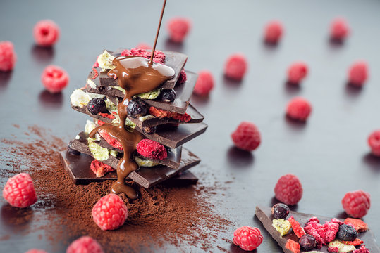 Sweet chocolate slices with fruits, cocoa powder and chocolate topping. sweet dessert on black background, image for patisserie