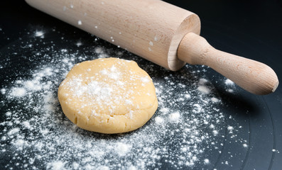 Ball of dough and rolling with flour pin on black